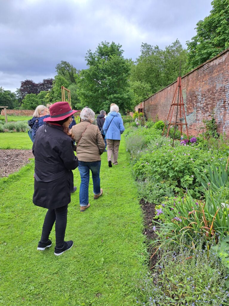 Visitors inside Wollaton Park walled garden, admiring a flower border on a dull day