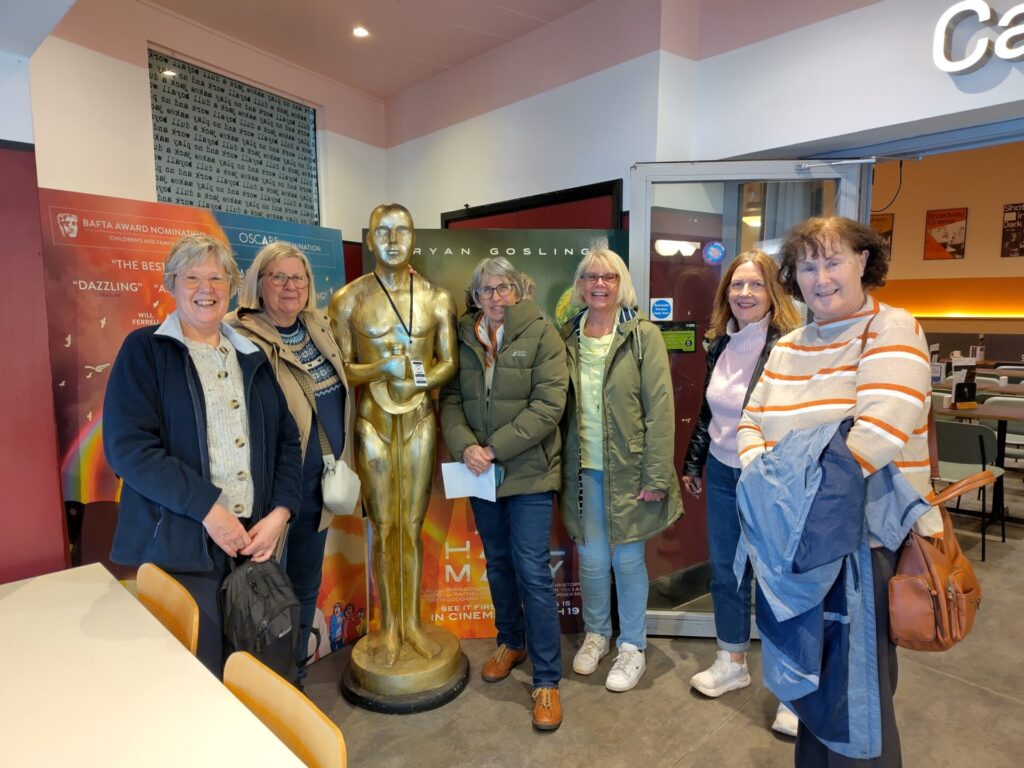A group of people standing either side of a human-sized Oscar statue in the foyer of the Broadway Cinema, Nottingham