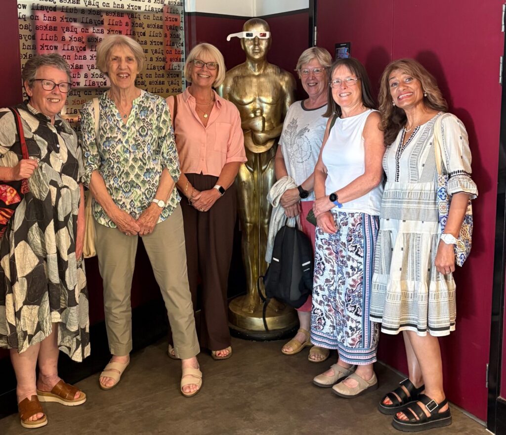 A group of people standing either side of a human-sized Oscar statue in the foyer of the Broadway Cinema, Nottingham. The statue wears 3D glasses.